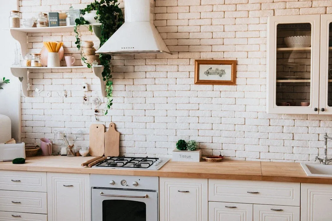 Kitchen sink with white subway tile and brick backsplash, shelving, and countertop
